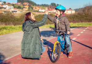 Mother and son giving five by success riding bicycle